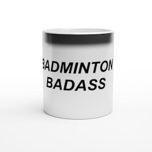 Peut inclure: Une tasse à café en céramique blanche avec un bord et une poignée noirs. La tasse porte l'inscription "BADMINTON BADASS" imprimée en noir sur le devant.