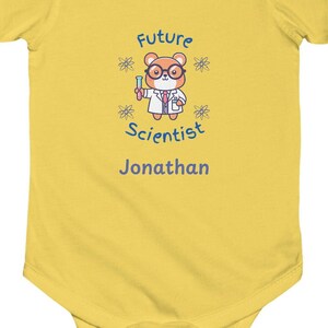 May include: Yellow baby onesie with a cartoon bear wearing a lab coat, glasses, and a face mask. The text "Future Scientist" is above the bear and the name "Jonathan" is below the bear.