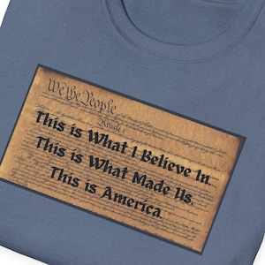 May include: A blue t-shirt with a print of the US Constitution document. The text on the print reads "We the People" and "This is what I believe in... This is what made us. This is America."