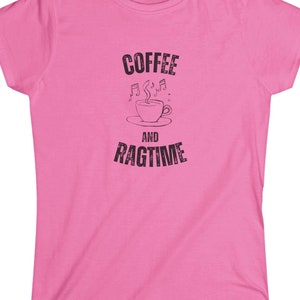 Può includere: Maglietta rosa da donna con una grafica nera che dice "Coffee and Ragtime" con una tazza di caffè stilizzata e note musicali.