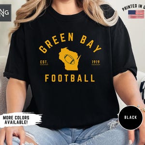 Peut inclure: Un t-shirt noir &agrave; manches courtes avec un imprim&eacute; graphique jaune indiquant GREEN BAY FOOTBALL, EST. 1919 et une silhouette de l'&Eacute;tat du Wisconsin contenant une ic&ocirc;ne de ballon de football. Le t-shirt porte un logo RNG et un drapeau PRINTED IN USA.