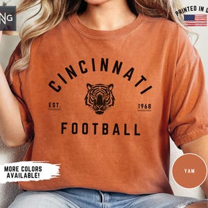 May include: A burnt orange t-shirt with a black graphic of a tiger and the text "Cincinnati Est. 1968 Football".