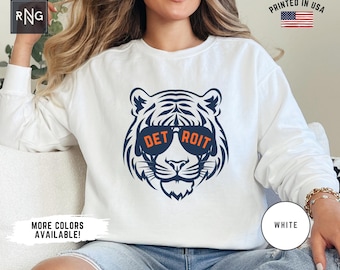 May include: White sweatshirt featuring a blue and orange tiger wearing sunglasses that read "DETROIT".