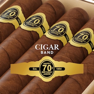 May include: A gold cigar band with the text "Happy 70th Birthday Jason Est. 1954" on a brown cigar.