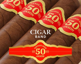 Könnte beinhalten: Nahaufnahme von vier braunen Zigarren mit roten und goldenen Etiketten. Die Etiketten lesen sich "Vintage Aged 50 Jason 1975". Der Text "Cigar Band" ist in Weiß dargestellt. Die Zigarren befinden sich in einer Holzkiste.