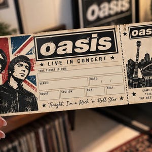 Może przedstawiać: Prostokątny papierowy bilet na koncert z zespołem Oasis, zawierający tekst Oasis Live in Concert, Tonight, I'm a Rock 'n' Roll Star oraz Some Might Say This Will Be The Best Night Ever, flagę Union Jack i ilustrację gitary.
