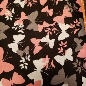 May include: Black fabric with a repeating pattern of pink, white, and gray butterflies. The butterflies are silhouetted against a dark background.