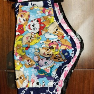 May include: Three layered face masks with a Paw Patrol character print. The outer layer is pink with white polka dots and the text "Paw Star" in black. The middle layer is navy blue with the text "Paw Star" in white. The inner layer is blue with a Paw Patrol character print.
