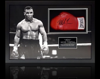 Peut inclure: Photo encadrée en noir et blanc de Mike Tyson sur un ring de boxe, avec un gant de boxe rouge signé et une plaque indiquant "Iron Mike Tyson". Le gant est signé au marqueur noir.