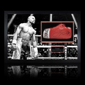 Könnte beinhalten: Gerahmte Schwarz-Weiß-Fotografie mit einem Boxer in einem Boxring. Ein roter Everlast-Boxhandschuh mit Unterschrift wird in einem kleineren Rahmen angezeigt. Das Bild enthält den Text "Floyd Mayweather Jr."