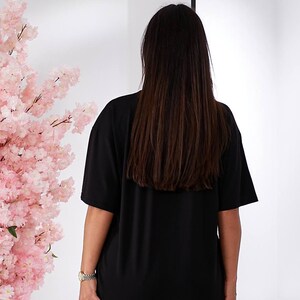 Puede incluir: Una camiseta negra de gran tama&ntilde;o con mangas cortas. La camiseta la lleva puesta una persona que lleva unos vaqueros azules claros.