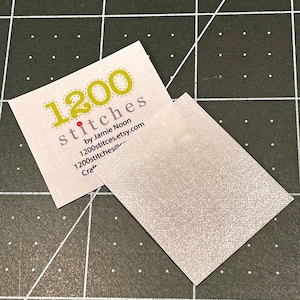 Pu&ograve; includere: Un biglietto da visita bianco con testo giallo che dice "1200 stitches by Jamie Noon 1200stitches.etsy.com Craft"