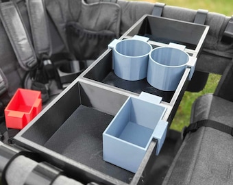 May include: A black stroller organizer with two gray cup holders and a gray rectangular storage compartment.