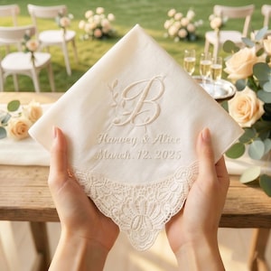 Puede incluir: Pañuelo de color marfil con detalles florales bordados y la letra "B". El pañuelo presenta los nombres "Harvey & Alice" y la fecha "March. 12. 2025". El borde inferior está adornado con encaje delicado. Un accesorio de boda.
