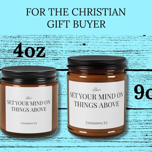 Könnte beinhalten: Zwei bernsteinfarbene Glaskerzen mit schwarzen Deckeln und weißen Etiketten. Die Etiketten tragen den Text "SET YOUR MIND ON THINGS ABOVE" und "Colossians 3:2". Die kleinere Kerze ist mit 4oz und die größere Kerze mit 9oz gekennzeichnet.