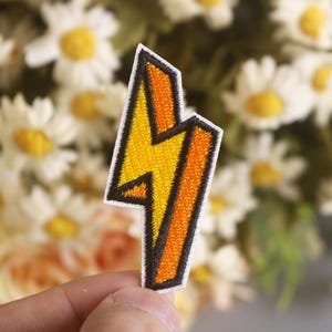 May include: A yellow and orange lightning bolt shaped iron-on patch with black outlines.