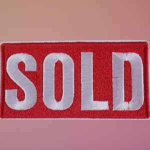 Peut inclure: Patch en tissu rouge avec du texte brodé blanc qui dit "SOLD".
