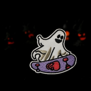 May include: Embroidered patch of a friendly ghost on a purple skateboard with red wheels. The ghost is white with a black smiling face. The patch has a white border against a black background.