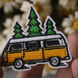May include: Yellow embroidered patch of a vintage van with three green trees on top. The van has a white roof and black windows.