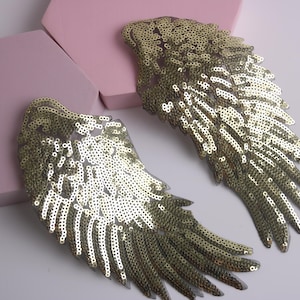 May include: Two gold sequined angel wings. The wings are made of a sheer fabric with gold sequins sewn on. The wings are about 6 inches tall and 4 inches wide.