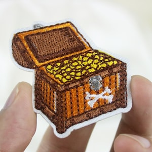 May include: A brown wooden treasure chest with a white skull and crossbones design. The chest is open and filled with gold coins.