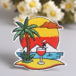 May include: Embroidered patch depicting a tropical sunset scene. The design includes a palm tree, a cocktail, and a colourful sunset over the ocean. The patch is outlined in white.