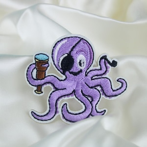May include: Purple embroidered octopus with an eyepatch holding a telescope. The octopus is smiling and has a friendly expression.