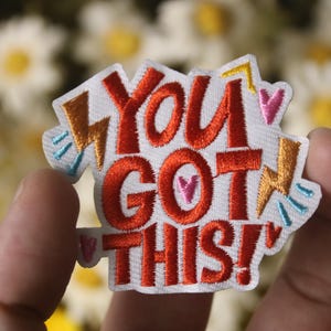 May include: White embroidered patch with the text "You got this!" in red, with yellow lightning bolts and pink hearts.