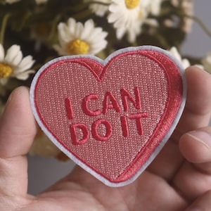 Może przedstawiać: Różowa łatka w kształcie serca z białymi szwami i napisem "I CAN DO IT" w kolorze białym.