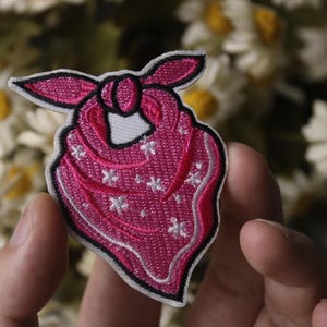 May include: Pink embroidered iron-on patch of a bandana with white stars.