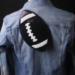 Puede incluir: Un parche de fútbol negro y blanco con lentejuelas en una chaqueta vaquera azul.