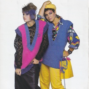 May include: Two people in vibrant knitwear. One wears a pink and blue vest over a black lace top and leather trousers. The other wears a blue vest, yellow trousers, and a patterned shirt. Accessories include a yellow beret.