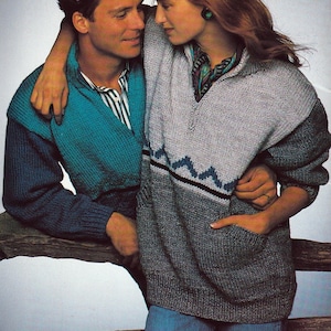 May include: A couple wearing knitted sweaters. The woman is wearing a gray sweater with a geometric design and a V-neck. The man is wearing a teal and navy blue sweater. The sweaters appear to be from the 1980s or 1990s.