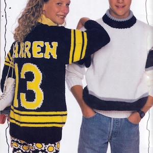 May include: A black and yellow knitted hockey jersey with the name "AREN" and the number "13" on the back. The jersey has yellow stripes on the sleeves and bottom. A white and grey sweater is also visible.