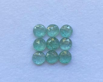 May include: Nine round, faceted gemstones in shades of teal and aqua are arranged in a grid pattern. The gems have a polished, reflective surface, and are set against a white background.