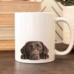May include: A white ceramic mug with a black handle and the text "But first, coffee" in a handwritten style. The mug is on a white surface. The mug is 4 inches tall.