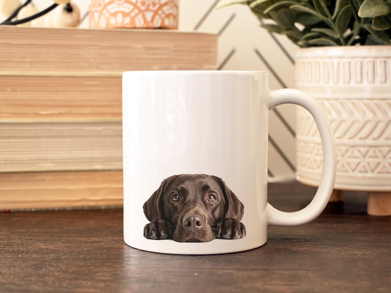 May include: A white ceramic mug with a black handle and the text "But first, coffee" in a handwritten style. The mug is on a white surface. The mug is 4 inches tall.