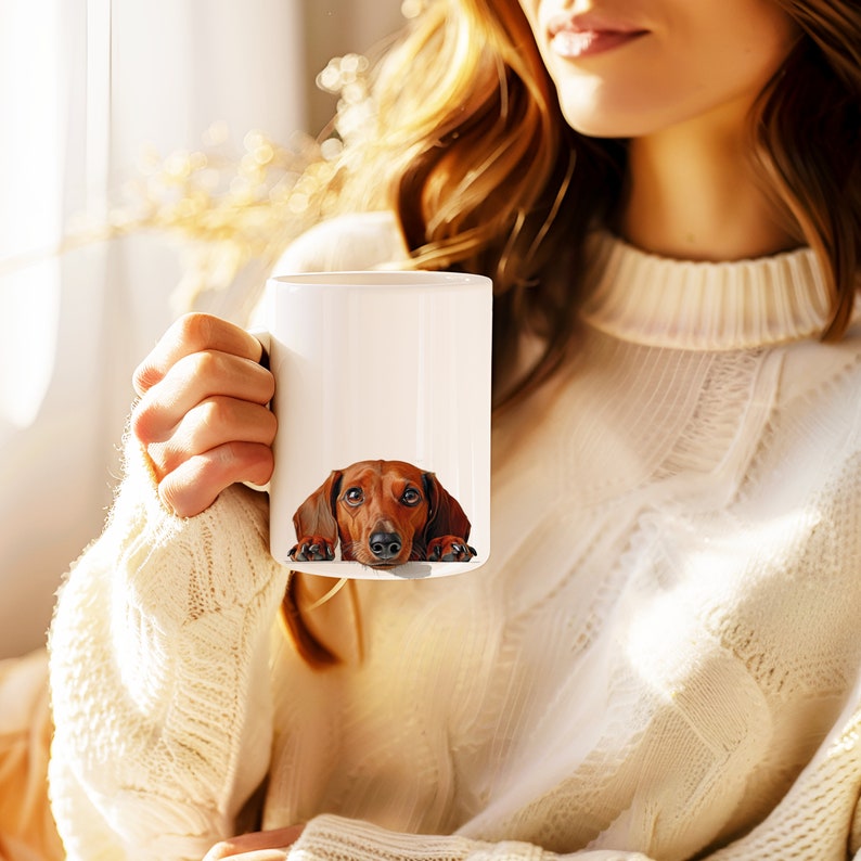 May include: A white ceramic mug with a brown dachshund peeking out from behind the rim. The dog has a brown and black nose and brown eyes.