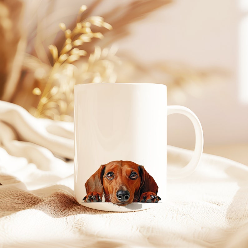 May include: A white ceramic mug with a brown dachshund peeking over the rim. The dog has brown eyes and a pink nose.