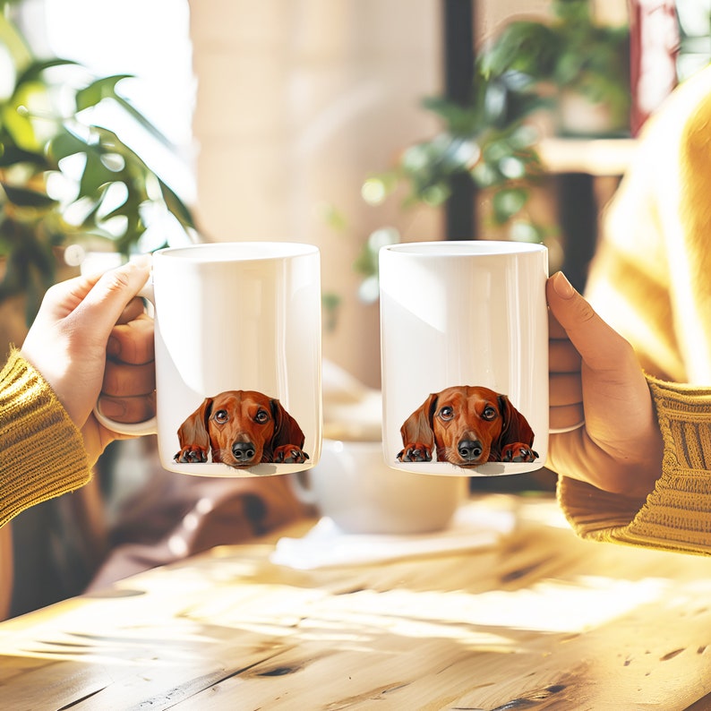 May include: Two white ceramic mugs with a dachshund dog peeking out from behind the rim of each mug. The dachshund is brown and tan with a black nose.