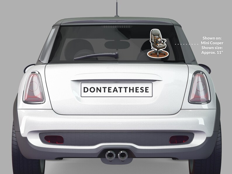 Puede incluir: Un Mini Cooper blanco con una pegatina en la luneta trasera que muestra un gato de dibujos animados en una silla de oficina. La pegatina mide aproximadamente 28 cm. La matr&iacute;cula dice "DONTEATTHESE".