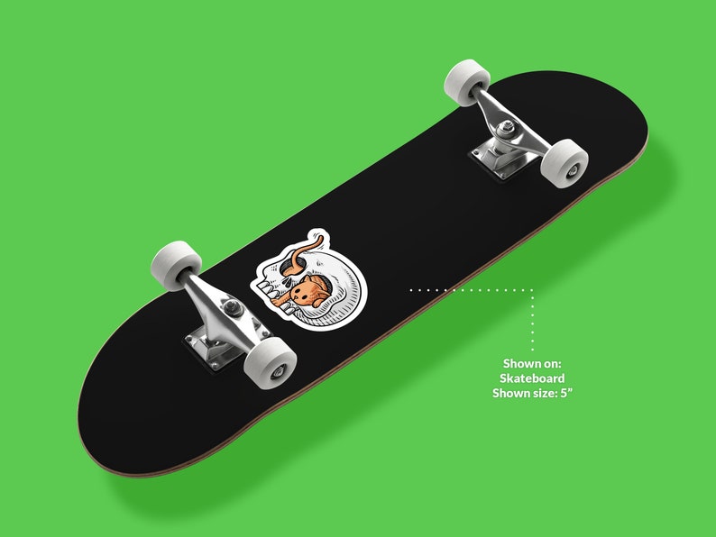 K&ouml;nnte beinhalten: Schwarzes Skateboard mit einem wei&szlig;en und orangefarbenen Totenkopf-Motiv. Gezeigt auf: Skateboard. Gezeigte Gr&ouml;&szlig;e: 5"