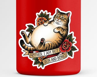 Könnte beinhalten: Ein roter Becher mit einem Tattoo-Design einer Katze. Die Katze ist braun und beige, mit einem großen Bauch, umgeben von Rosen und einem Banner mit der Aufschrift "MOTHER, I AM BUT SKIN AND BONES."