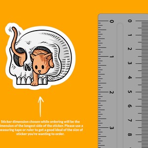K&ouml;nnte beinhalten: Ein wei&szlig;er Totenkopf-Aufkleber mit einer kleinen orangefarbenen Katze, die aus der Augenh&ouml;hle schaut. Der Aufkleber wird neben einem Lineal gezeigt, um die Gr&ouml;&szlig;e zu veranschaulichen. Die beim Bestellen gew&auml;hlte Aufkleberdimension entspricht der Dimension der l&auml;ngsten Seite des Aufklebers. Bitte verwenden Sie ein Ma&szlig;band oder ein Lineal, um eine gute Vorstellung von der Gr&ouml;&szlig;e des Aufklebers zu bekommen, den Sie bestellen m&ouml;chten.