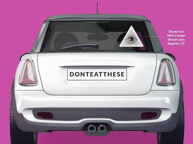 Op de afbeelding: Witte Mini Cooper met een zwart-witte sticker op de achterruit. De sticker is een driehoek met een oog erin. De tekst "DONTEATTHESE" staat op de bumper. Getoond op: Mini Cooper. Getoonde maat: Ongeveer 11 cm