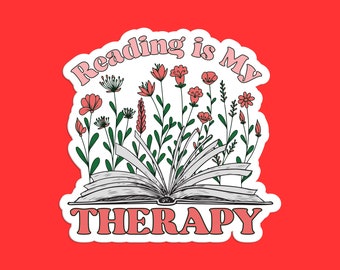 Può includere: Un adesivo con un libro aperto e fiori, con il testo "Reading is my therapy" in lettere rosa.