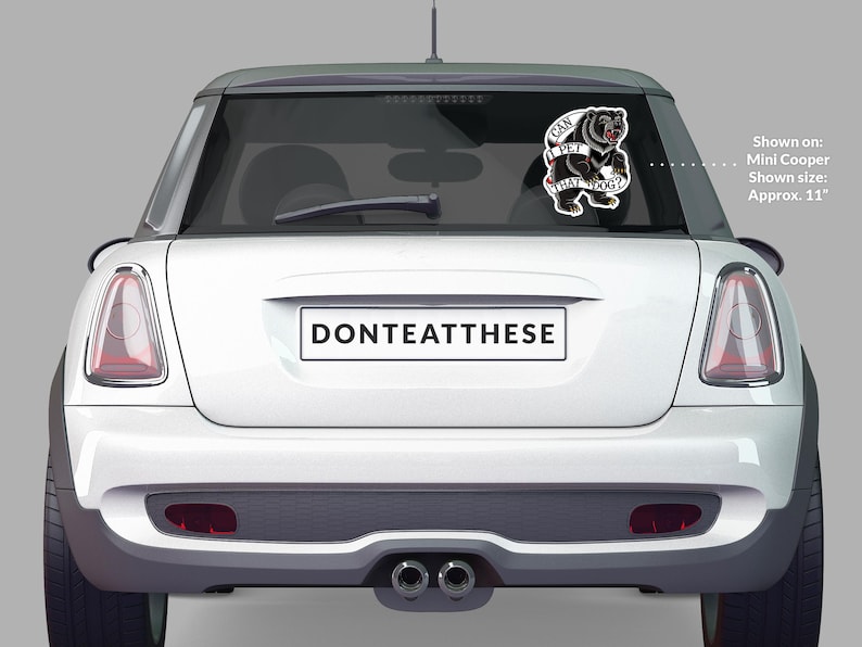 May include: A white Mini Cooper with a sticker on the rear window. The sticker features a black bear with the text "CAN I PET THAT DOG?" in a banner. The license plate reads "DONTEATTHESE".