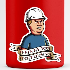 Puede incluir: Vaso rojo con una ilustración de dibujos animados de un hombre con casco blanco y camisa azul. La imagen incluye una pancarta con el texto "THAT'S MY TOOL I DON'T KNOW YOU."