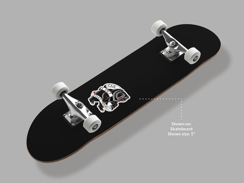 May include: Black skateboard with white wheels and silver hardware. A sticker with a black dog and the text "CAN I PET THAT DOG?" is affixed to the board. The skateboard is shown on a gray background.