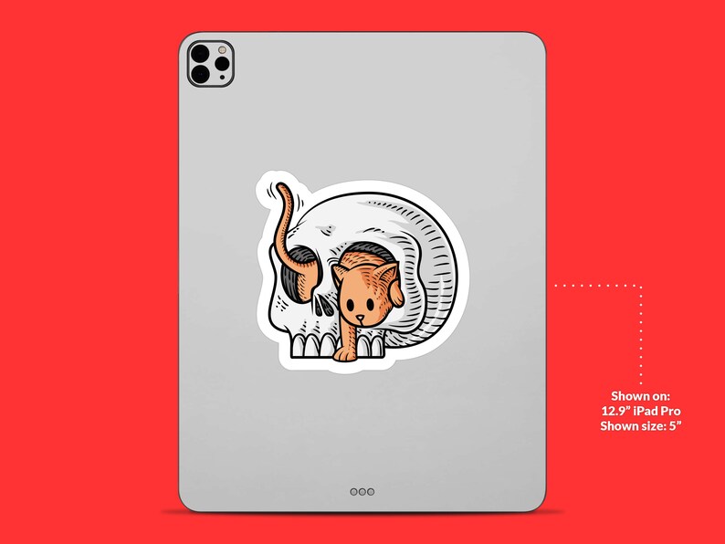 K&ouml;nnte beinhalten: Ein Aufkleber mit einer Cartoon-Illustration einer Katze, die aus einem Sch&auml;del schaut. Die Katze ist orange und wei&szlig;, der Sch&auml;del ist schwarz und wei&szlig;.